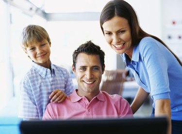 parents with their son looking at a computer