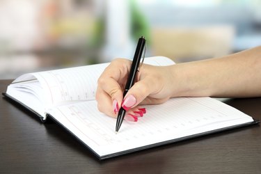 Hand signing in notebook, on bright background