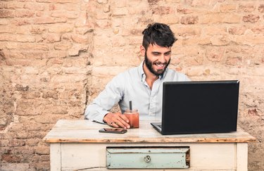 Young hipster guy sitting at vintage desk with laptop