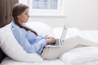 Close-up view of Woman using laptop on her bed