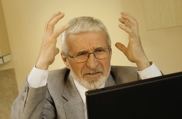 Mature businessman with hands raised in frustration and laptop computer, close-up