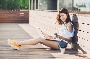 Young trendy girl using a laptop outdoors