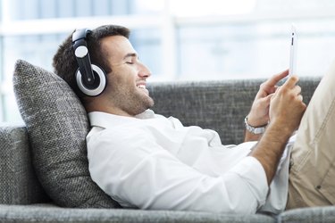 Man on sofa with headphones and digital tablet