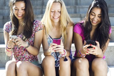 three girls chatting with their smartphones