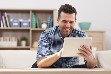 Smiling handsome man using digital tablet at home