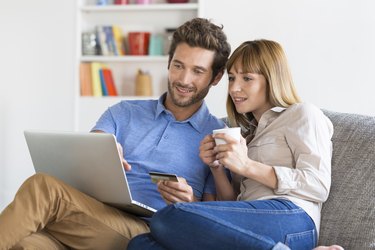 Mid adult couple shopping using laptop and credit card