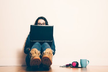 Nerd girl sitting on the floor with a laptop