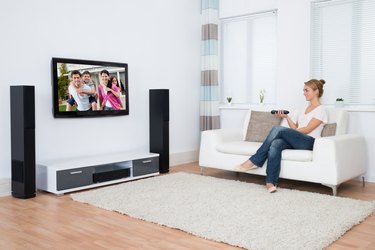 Woman Watching Television While Sitting On Sofa