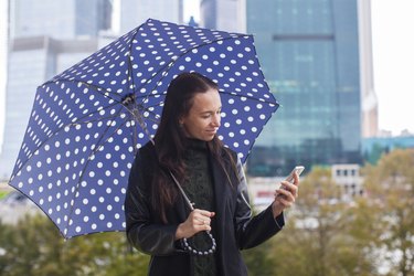 Young woman talking on the phone with umbrella in hand