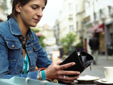 Woman sitting at outdoor cafe looking in purse (focus on woman)