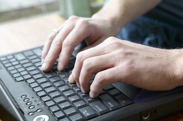 Man typing on laptop keyboard
