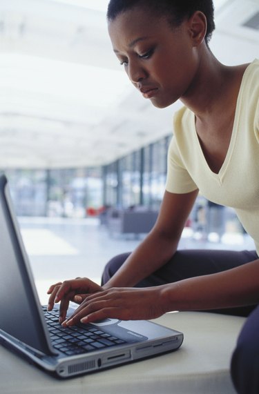 Side profile of a young woman working on a laptop
