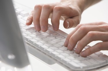 Close-up of a mature person typing on a computer keyboard
