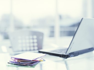 Laptop on desk with pile of CD cases on desk, close up