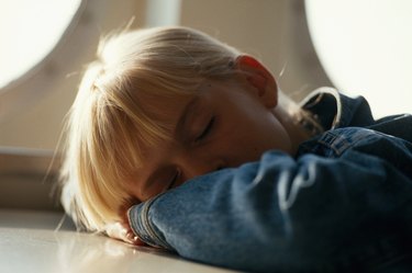 Girl (4-7) resting on table, close-up