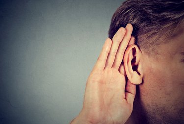 man holds hand near ear and listens carefully