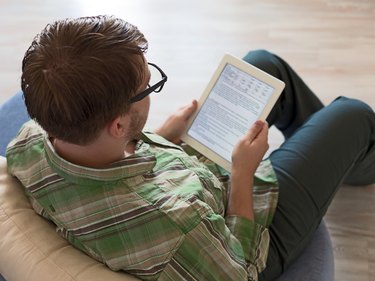 Young Man using Tablet Computer with wood floor Background