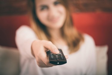 Smart tv and hand pressing remote control.