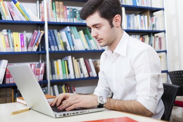 Guy using his laptop in a library