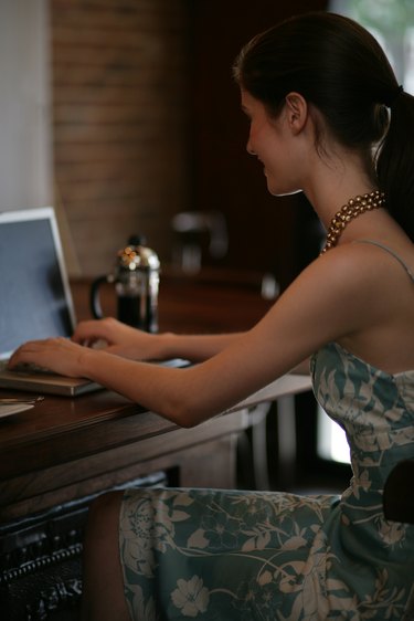 Young woman using laptop at bar in cafe.