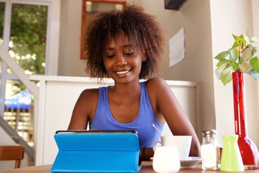 Smiling young woman using digital tablet at cafe