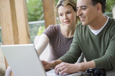 Couple uploading photos to laptop computer