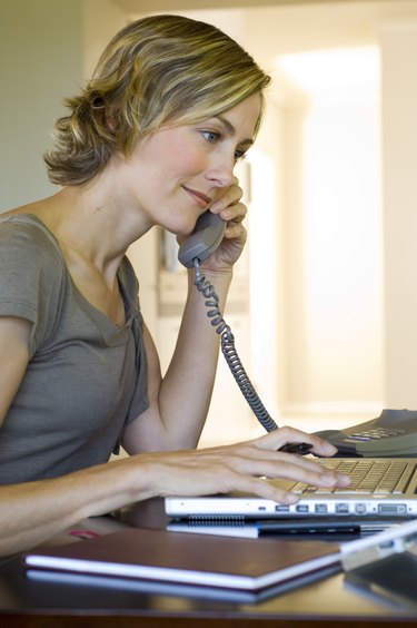 Woman talking on phone and using laptop computer