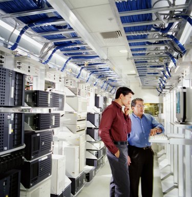 Two businessmen using computer in server room