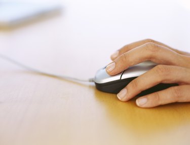 close-up of a human hand holding a computer mouse