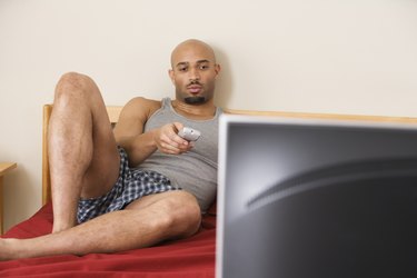 African man watching television in bed