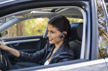 Woman in car with cell phone earphone