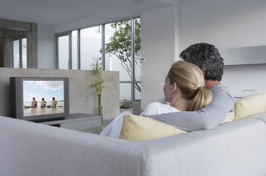 Couple relaxing on sofa watching television, rear view