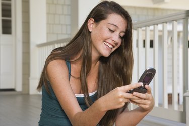 Smiling teenage girl using cell phone