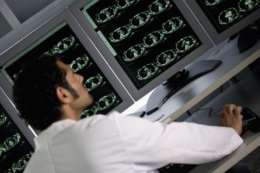 Rear view of doctor in front of MRI monitor screens