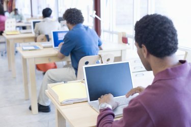 People in office working on computers, rear view