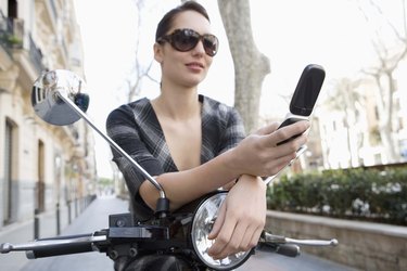 Woman on moped with cell phone