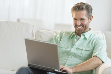 Happy Man Using Laptop On Sofa