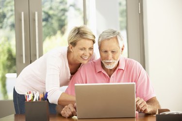 Adult Daughter And Senior Father Using Laptop At Home
