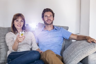 Couple watching a movie with a video projector on sofa