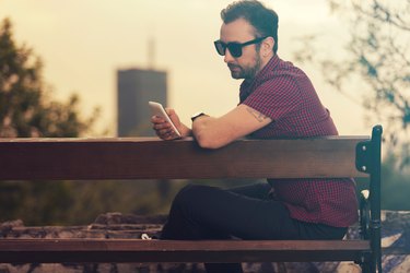 Modern guy using cellphone outdoors.