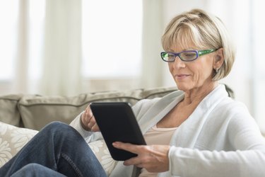 Woman Using Tablet Computer On Sofa