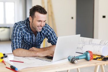 Smiling construction worker working with laptop