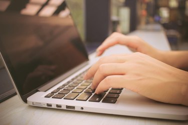 Female hands typing on keyboard of laptop