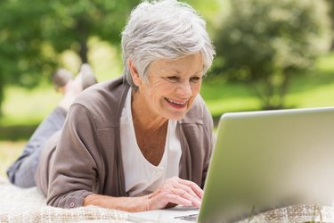Smiling senior woman using laptop at park