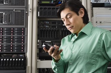 Man in server room with cell phone