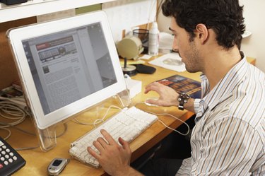 Male office worker at workstation, view over shoulder