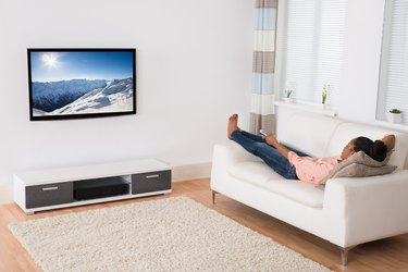 African Woman Lying On Sofa Watching Television