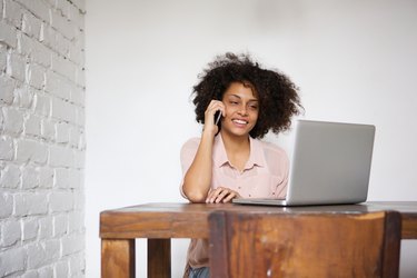 Woman working at home with laptop and mobile phone