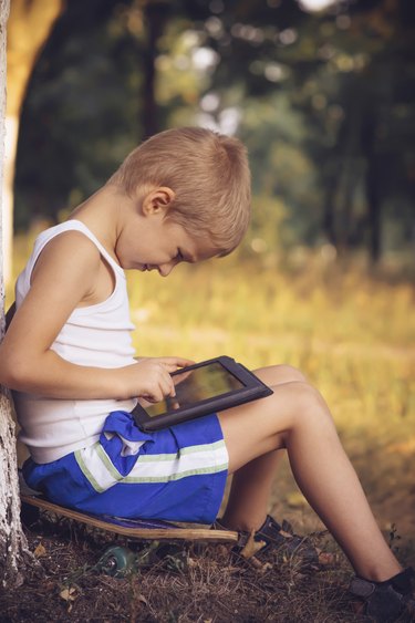 Boy Child playing with Tablet PC Outdoor