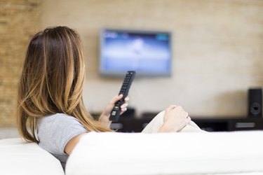 Young woman on couch watching a flatscreen tv